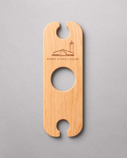 A wooden Wine Butler that holds two glasses and balances on the neck of a bottle of wine.