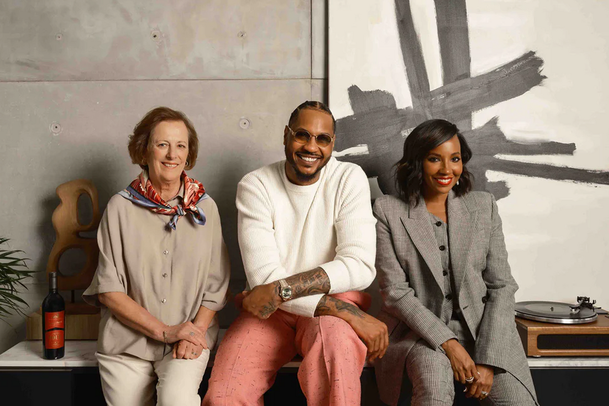 Three people sitting together in a room with a painting on the wall.